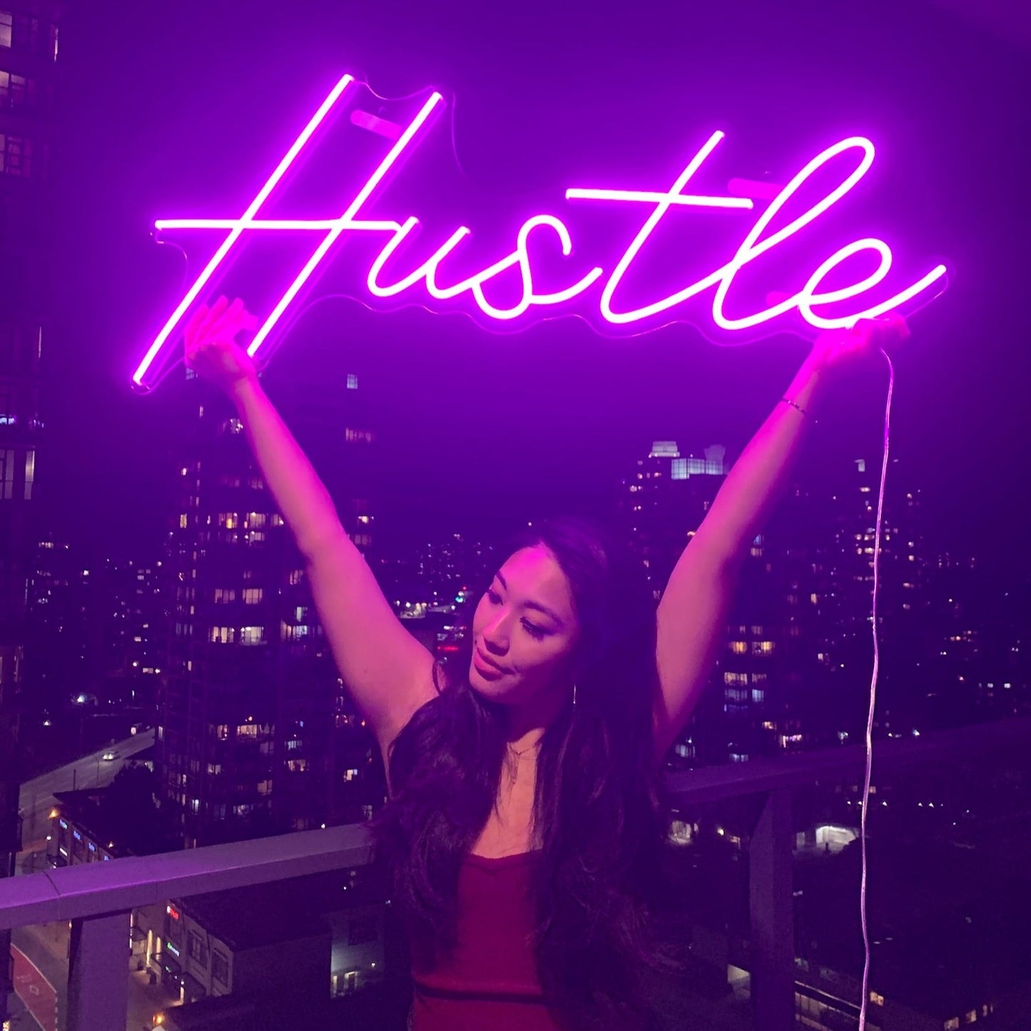 girl holding up hustle neon sign in apartment in vancouver
