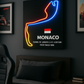 Neon sign of a racing car silhouette with Monaco information on a dark wall.