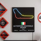 Neon sign of a race track layout with Italian flag and race details on a black background, mounted on a wall.