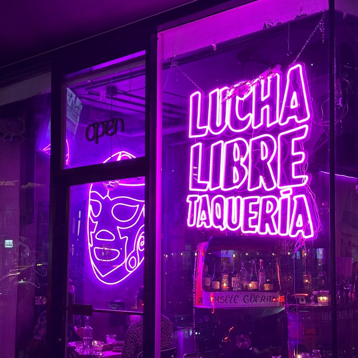 Neon sign for Lucha Libre Taqueria in a purple-lit restaurant interior.