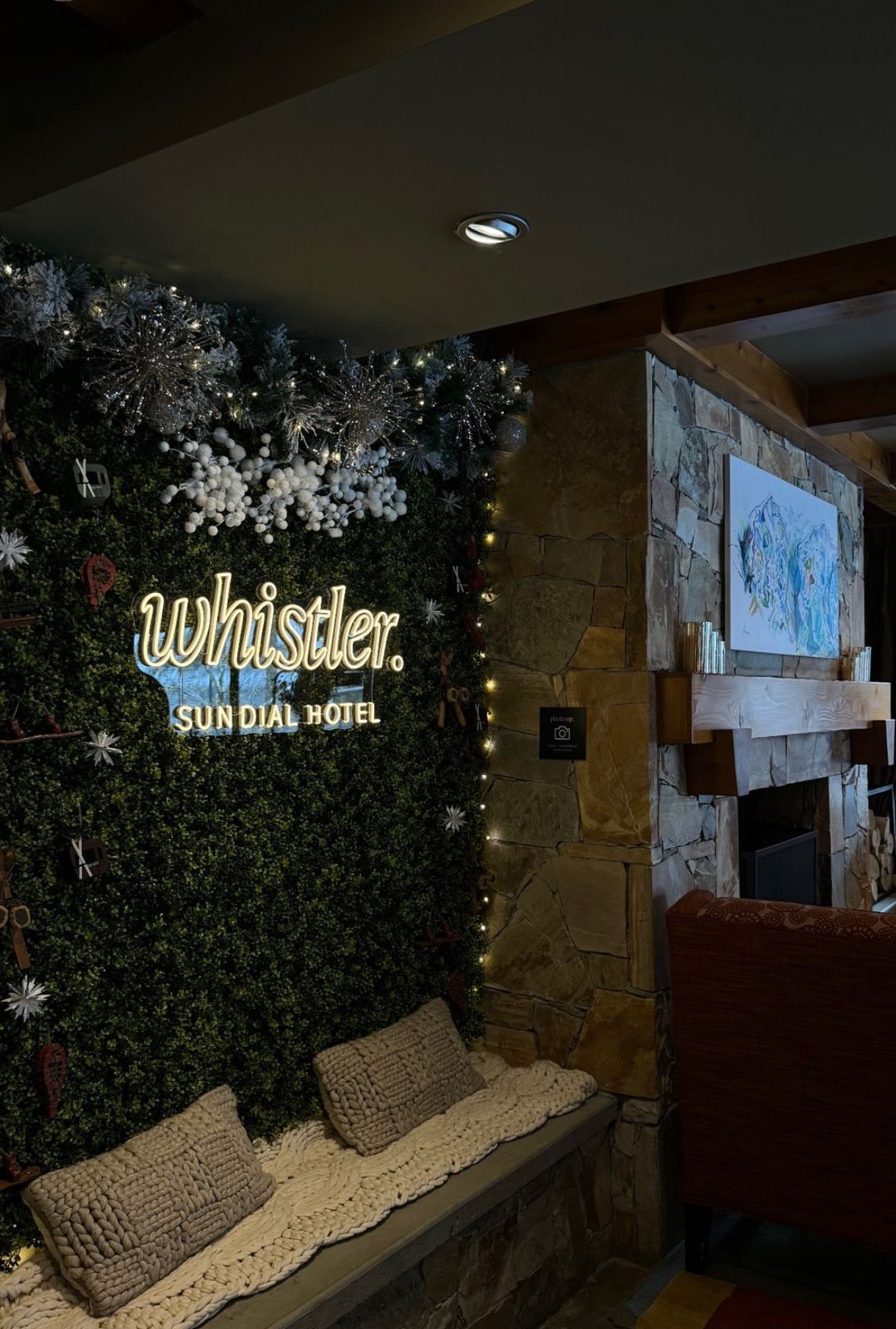 warm white neon sign for hotel in whistler, with a grass wall backdrop