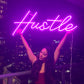 girl holding up hustle neon sign in apartment in vancouver